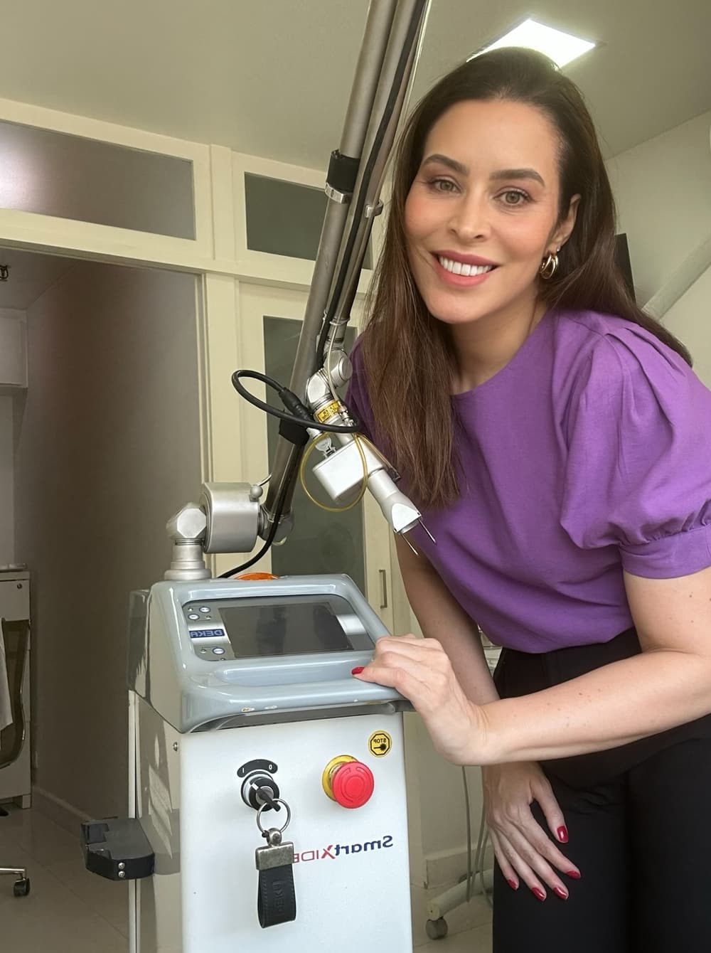 Dra. Ana Flávia Borges de Paula ao lado do equipamento de Laser CO₂ no consultório